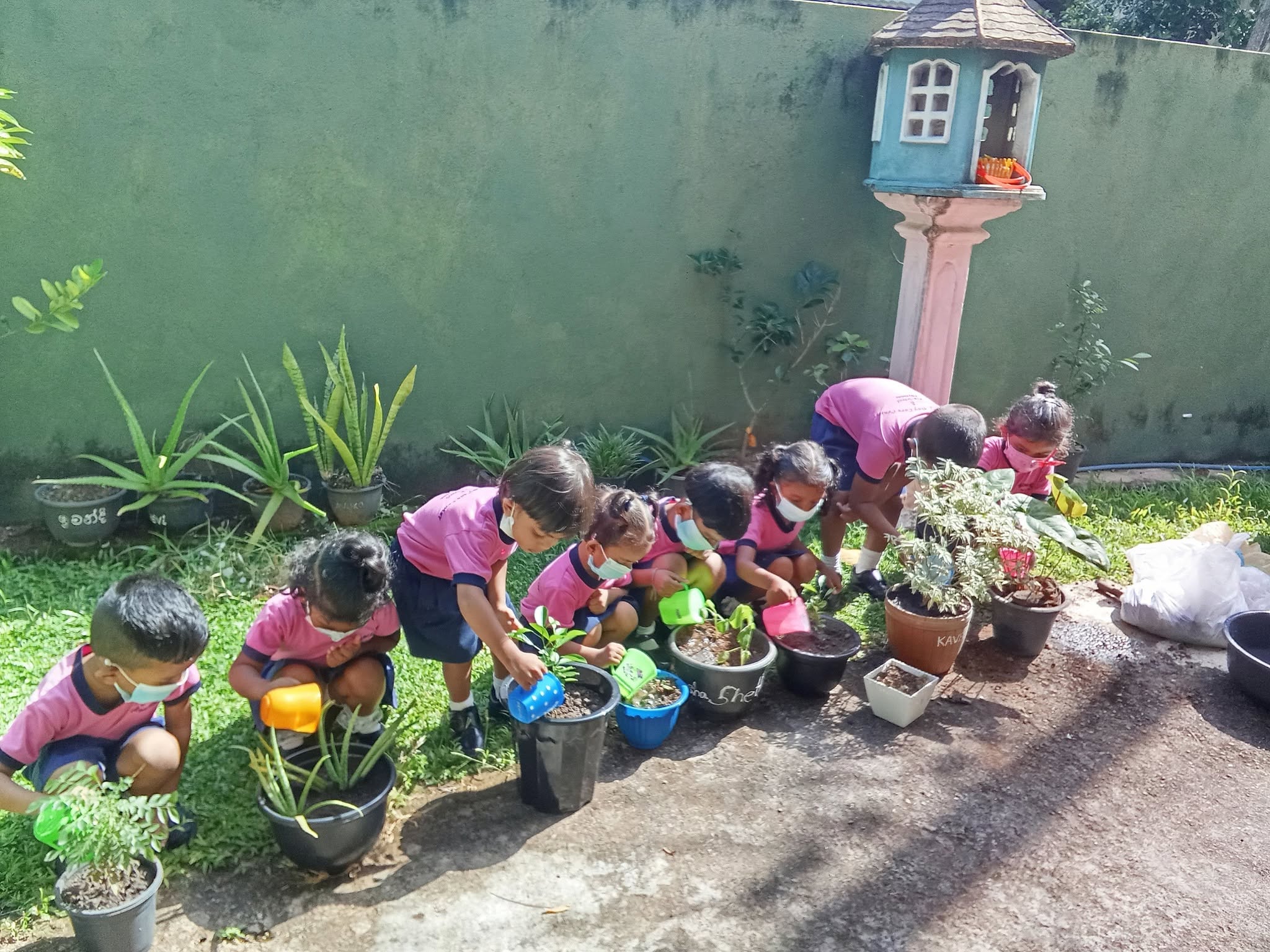 Children watering potted plants in the garden